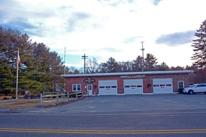 A Rehoboth Fire Department firehouse: an older brick station with three bay doors and a flag out front.